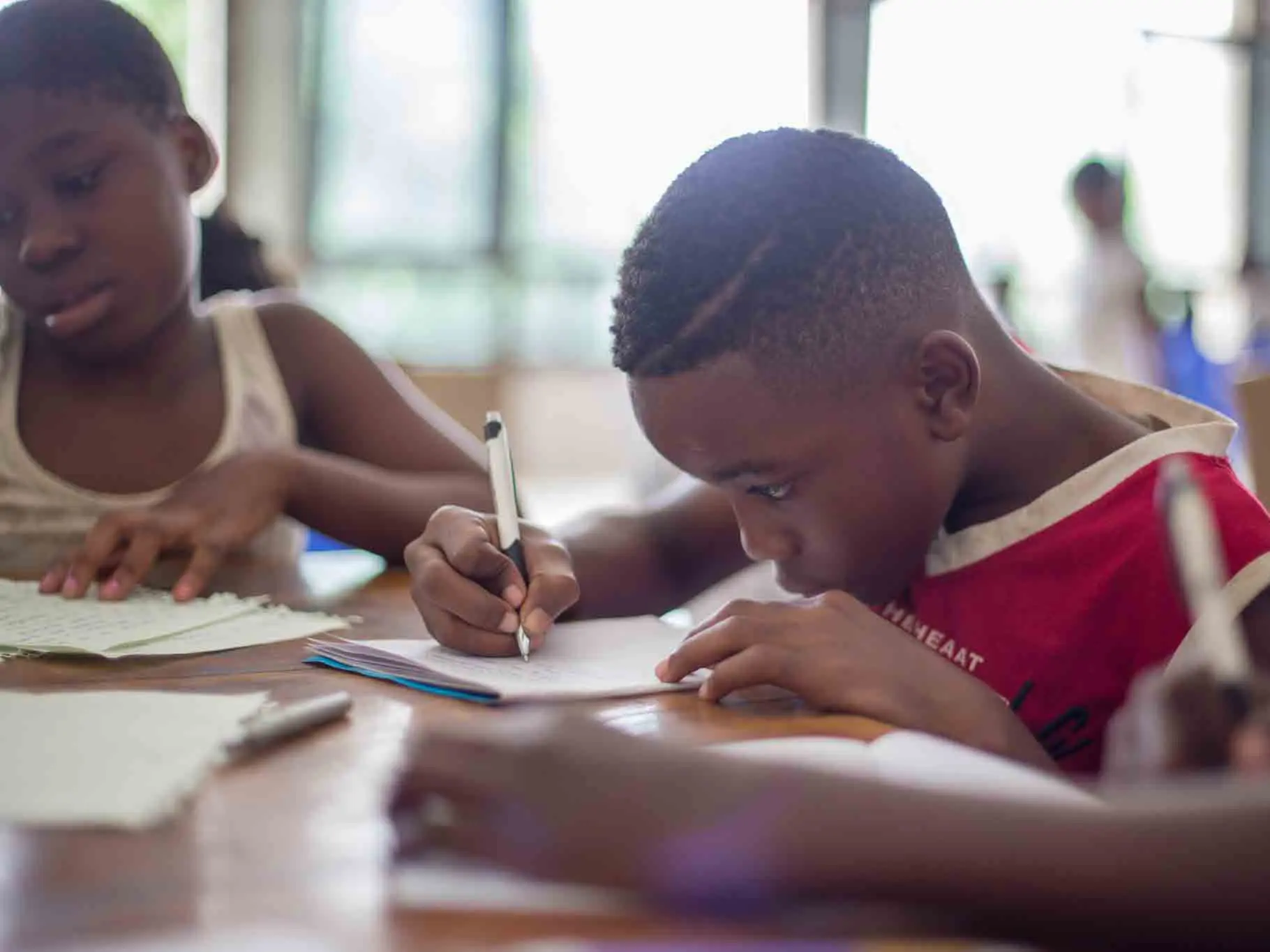 Student concentrating on writing at classroom desk