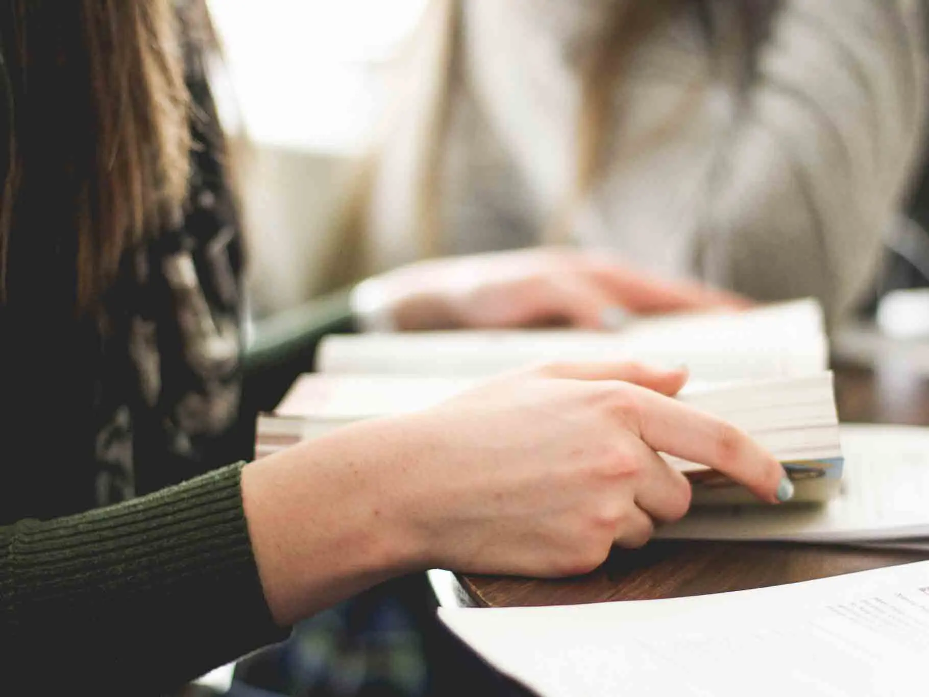 Hands pointing at open book on table