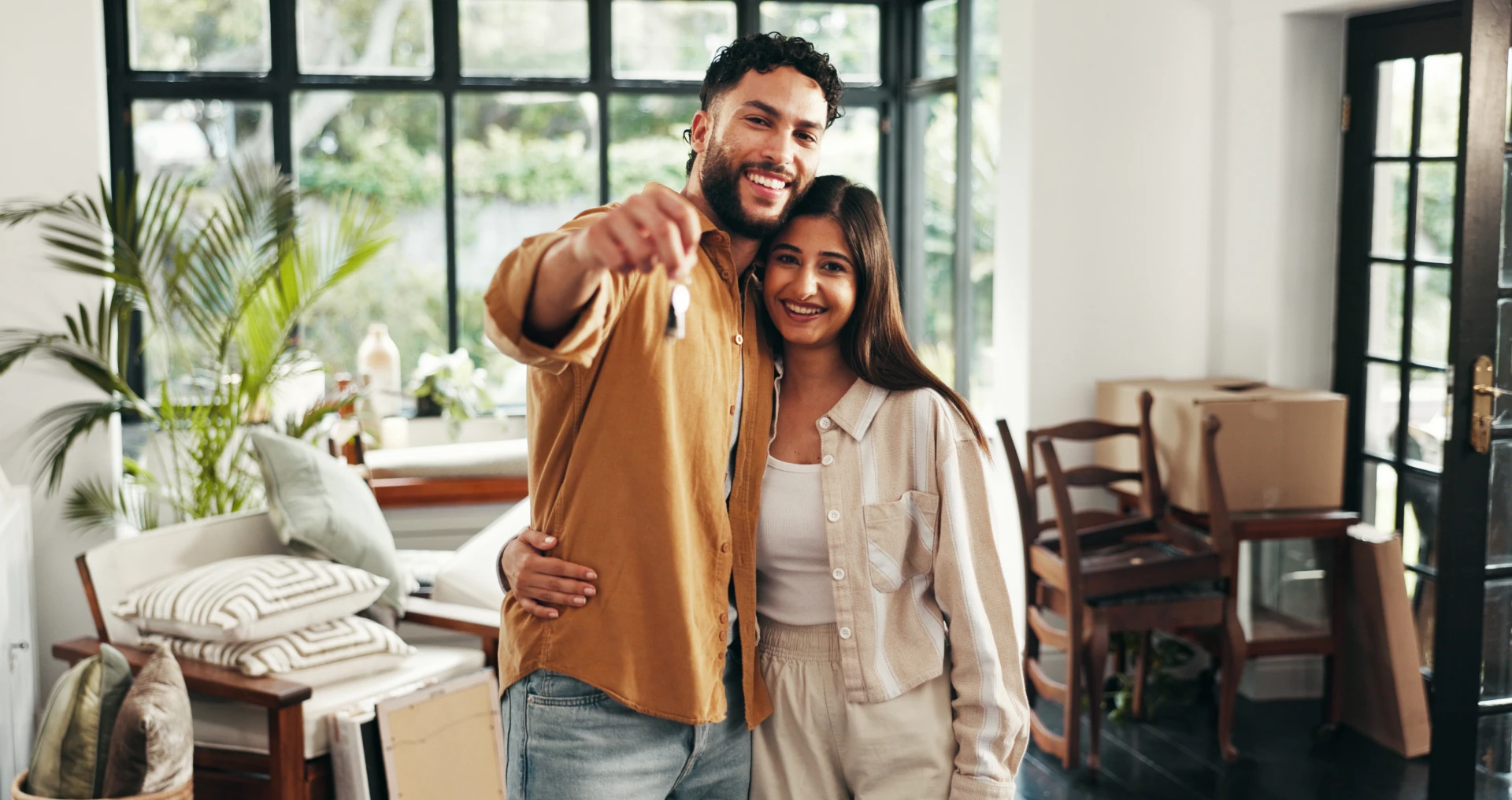 Smiling couple holding house keys in new home