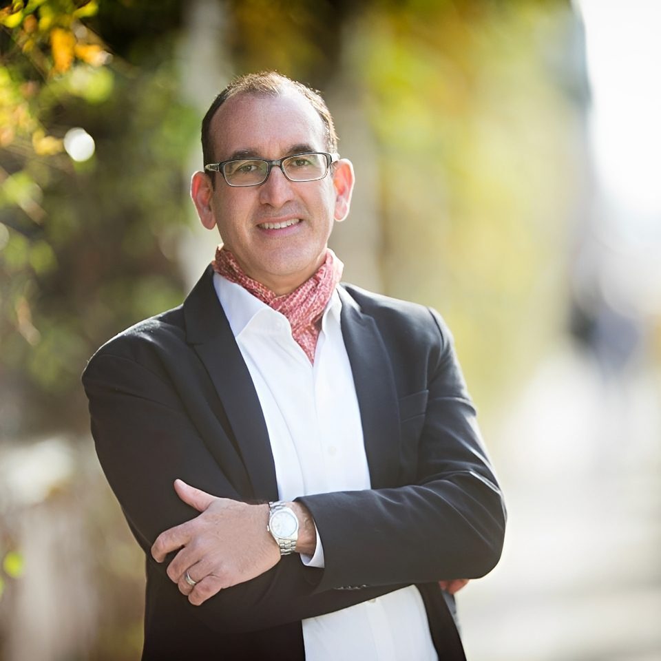 Smiling man with glasses and scarf outdoors